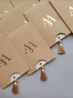 six business cards with tassels on top of each one and the letter a in gold foil