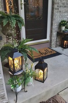 two lanterns are sitting on the front porch next to plants and a door mat that says hello