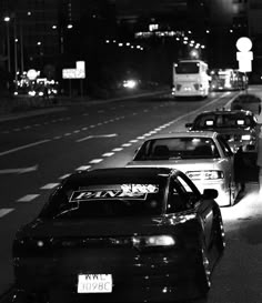 several cars are parked on the side of the road at night, with one person standing next to it