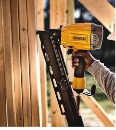 a man is holding a drill and nailing the side of a wooden structure with his right hand