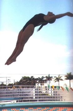 a woman diving into the pool with her legs in the air and head above water