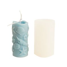 a blue candle with seashells and starfish on it next to a white pillar