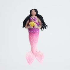 a pink and purple mermaid ornament hanging from a string on a white background