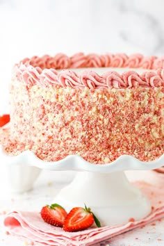 a strawberry cake with pink frosting and sprinkles on a white plate