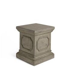 a cement pedestal with an intricate design on the top and base, sitting in front of a white background