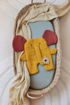 a stuffed animal in a wicker basket hanging on the wall next to a blanket