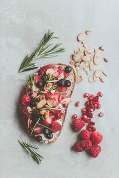 toast with berries, almonds and rosemary on it next to some other food items