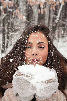 a woman blowing snow on her face in the woods