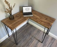 a laptop computer sitting on top of a wooden desk next to a vase with flowers