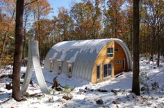 a small building in the middle of some trees with snow on it's ground