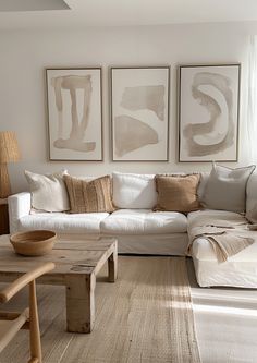 a living room filled with white furniture and paintings on the wall above it's couch