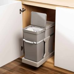 a grey trash can sitting inside of a kitchen cabinet