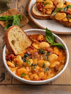 a bowl of soup with bread on the side and another bowl full of stew next to it