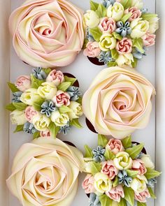 four cupcakes decorated with flowers in a box