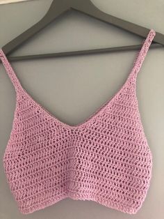 a pink crocheted bralet hanging on a hanger