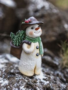 a snowman figurine with a hat and scarf on top of a rock