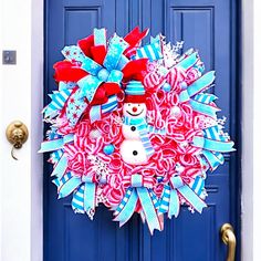 a red, white and blue christmas wreath with a snowman on the front door