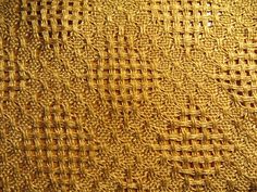 close up view of the textured surface of an old gold colored cloth or curtain