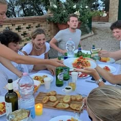 a group of people sitting around a table with plates of food and drinks in front of them