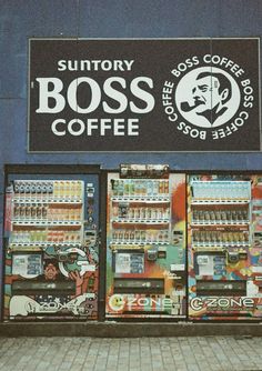 two vending machines sitting next to each other in front of a coffee shop sign