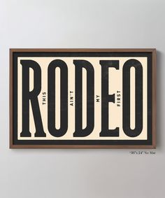 a wooden sign that says rodeo with black letters on white and brown background, hanging on the wall