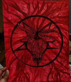 a person holding up a red painting with a bull head on it's face