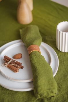 a plate with cinnamon sticks on it next to a green napkin and some other items