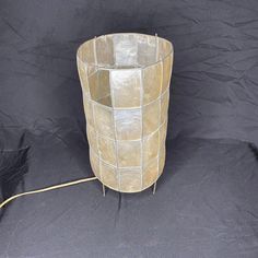 a vase sitting on top of a black cloth covered floor next to a wire fence