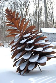 a pine cone made out of spoons sitting on top of the snow covered ground