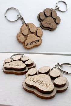 wooden keychains with engraved names and paw prints are shown on a white surface