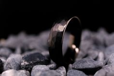 a wedding ring sitting on top of rocks in front of some stones and gravel with black background