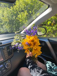 a person sitting in the driver's seat of a car holding a bouquet of flowers