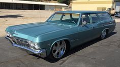 an old green station wagon parked in a parking lot