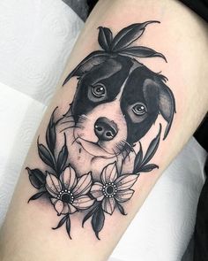 a black and white dog with flowers around it's neck is on the arm