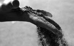 someone is throwing sand into the air with their hand on top of it in black and white