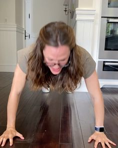 a woman is doing push ups on the floor with her hands and feet spread out