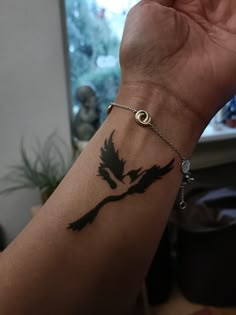 a woman's arm with a black bird tattoo on the wrist and an eye