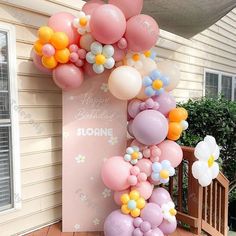 a bunch of balloons that are on the side of a building with flowers in them