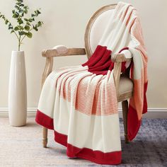 a chair with a red and white blanket draped over it next to a potted plant