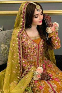 a woman in a yellow and pink bridal outfit sitting on a couch with her hands behind her head