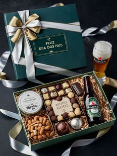 a beer and assorted snacks in a green gift box with ribbon around the edges