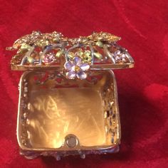 an ornate gold box with flowers and leaves on the lid sitting on a red velvet surface