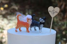 two cats on top of a white cake with a wooden heart and sign that says mr & mrs