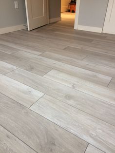 an empty room with wood flooring and white door way leading to another room in the background