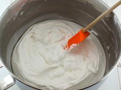 an orange spatula in a metal bowl filled with whipped cream