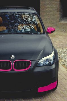 a black car with pink trim parked in front of a building