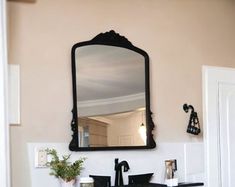 a bathroom sink sitting under a large mirror next to a doorway with a potted plant on it