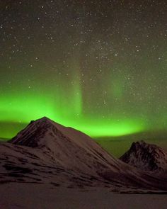 an aurora bore is seen in the sky above mountains