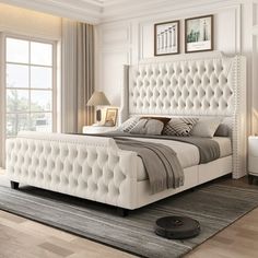 a white bed sitting in a bedroom on top of a hard wood floor next to a window