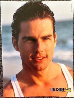 a close up of a person wearing a tank top near the ocean and sand with water in the background